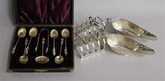 A pair of silver sauceboats, a pair of silver toastracks and a cased set of silver spoons with tongs.